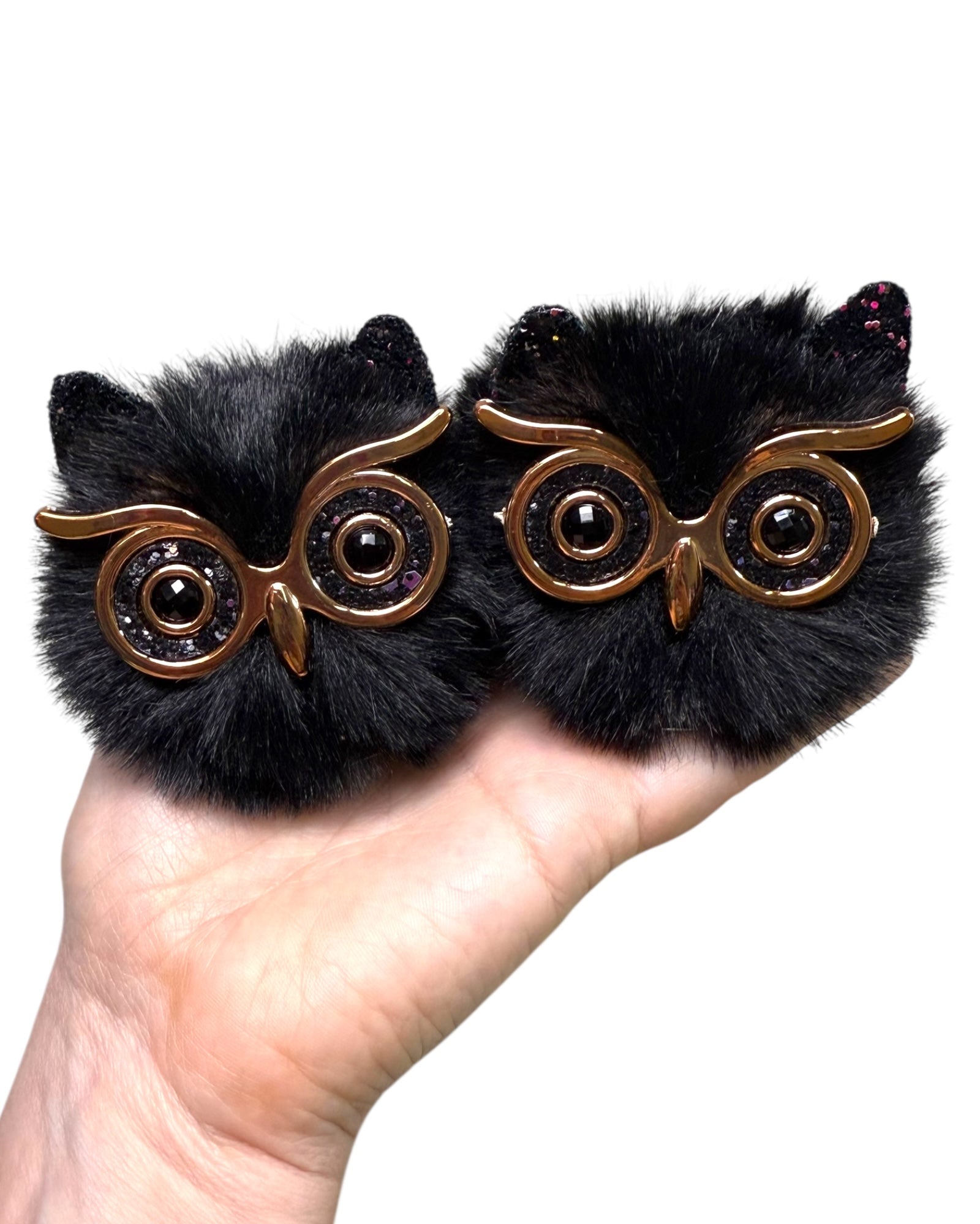 Black Owl Space Bunz held in a hand, fluffy faux fur pom pom hair clips with owl eyes.