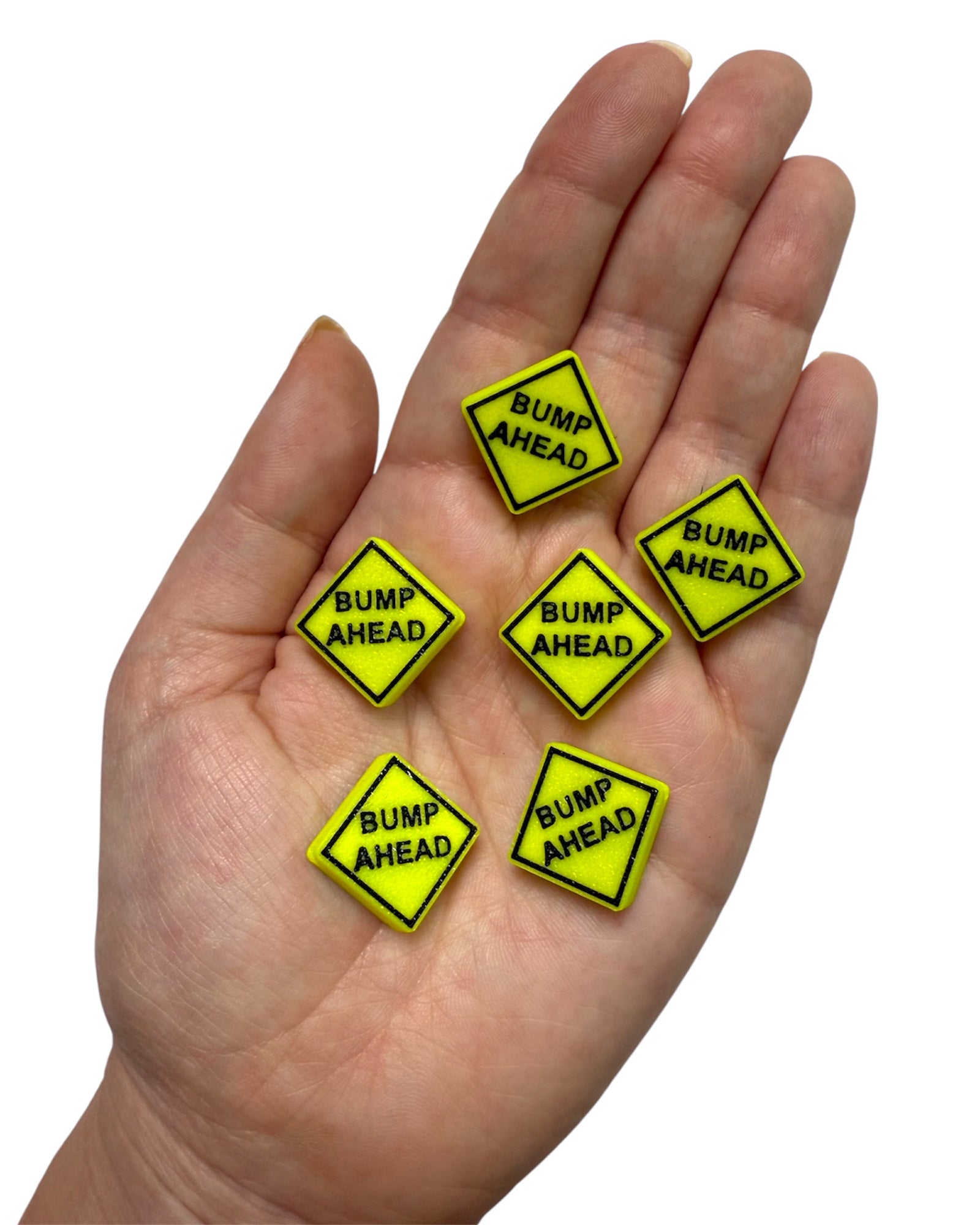 Hand holding six yellow 'Bump Ahead' signs kandi bead on a white background
