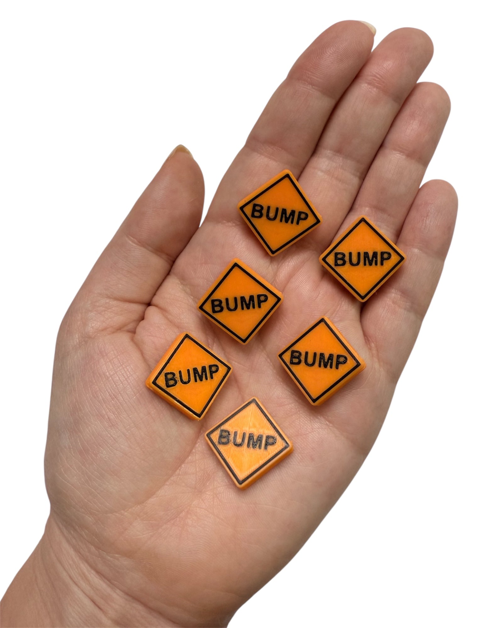 Hand holding six orange 'BUMP' kandi bead signs on a white background