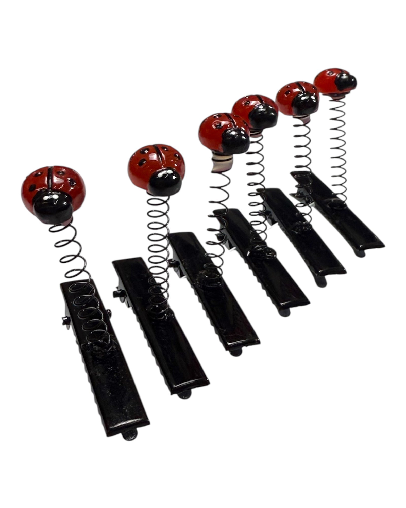 Set of six black clips with red and black ladybug designs on springs against a white background