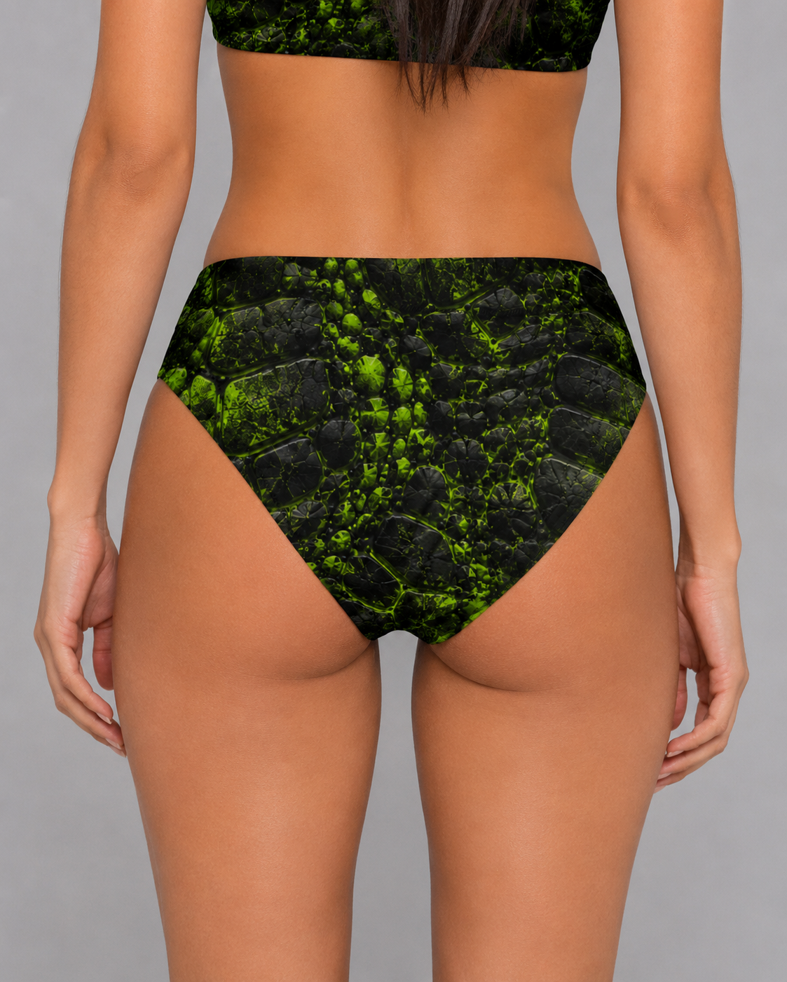 Back view of high-waisted bikini bottoms in black and neon green cracked, prehistoric-textured print.