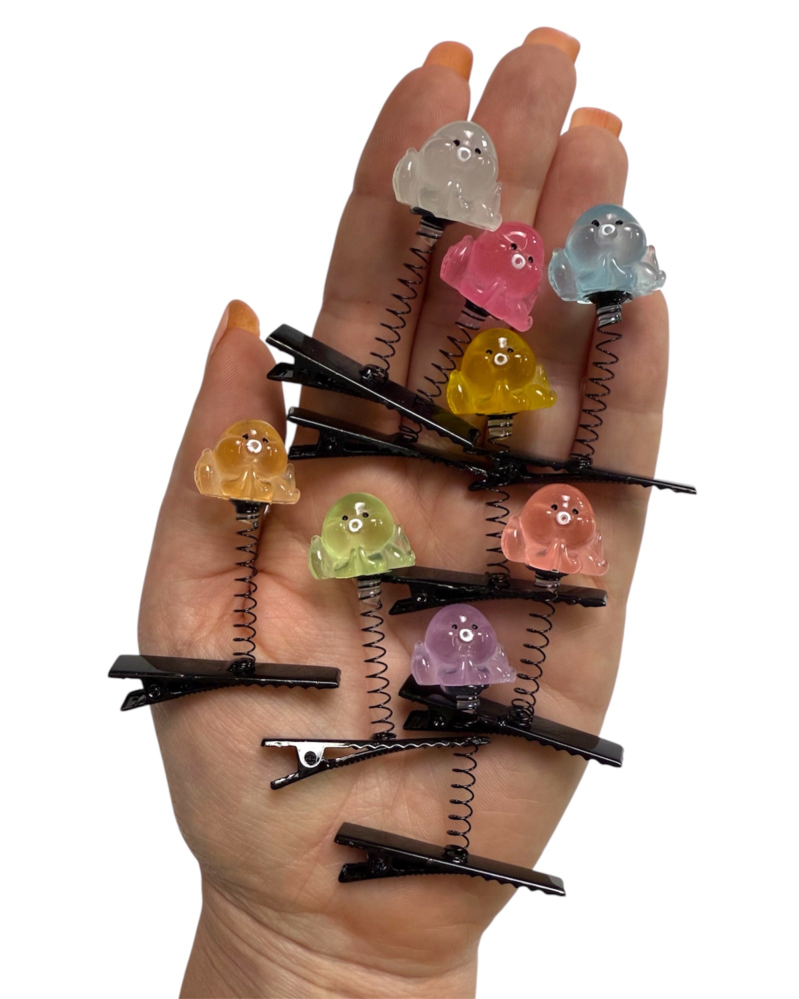 Hand holding colorful hair clips with spring mechanisms on a white background