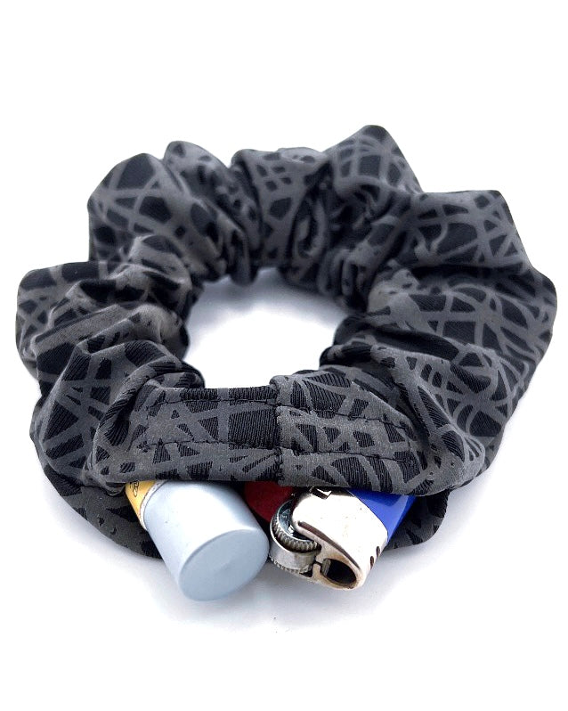 The String Theory Stashie featuring a sleek black geometric pattern with a discreet 2-inch Velcro® pocket for storing small essentials.