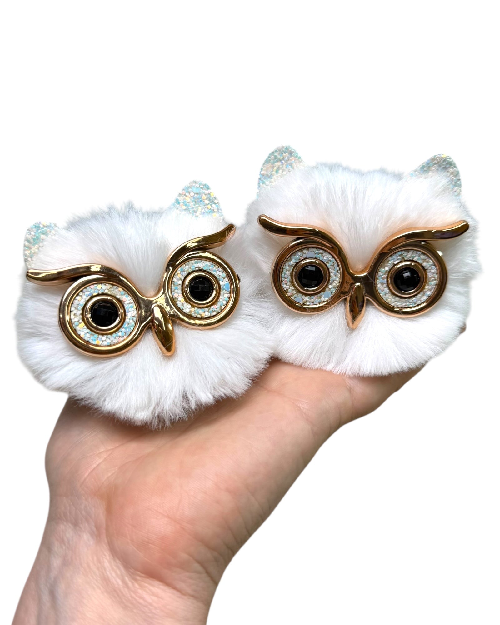 White Owl Space Bunz held in a hand, fluffy pom pom hair accessories with owl face detail.