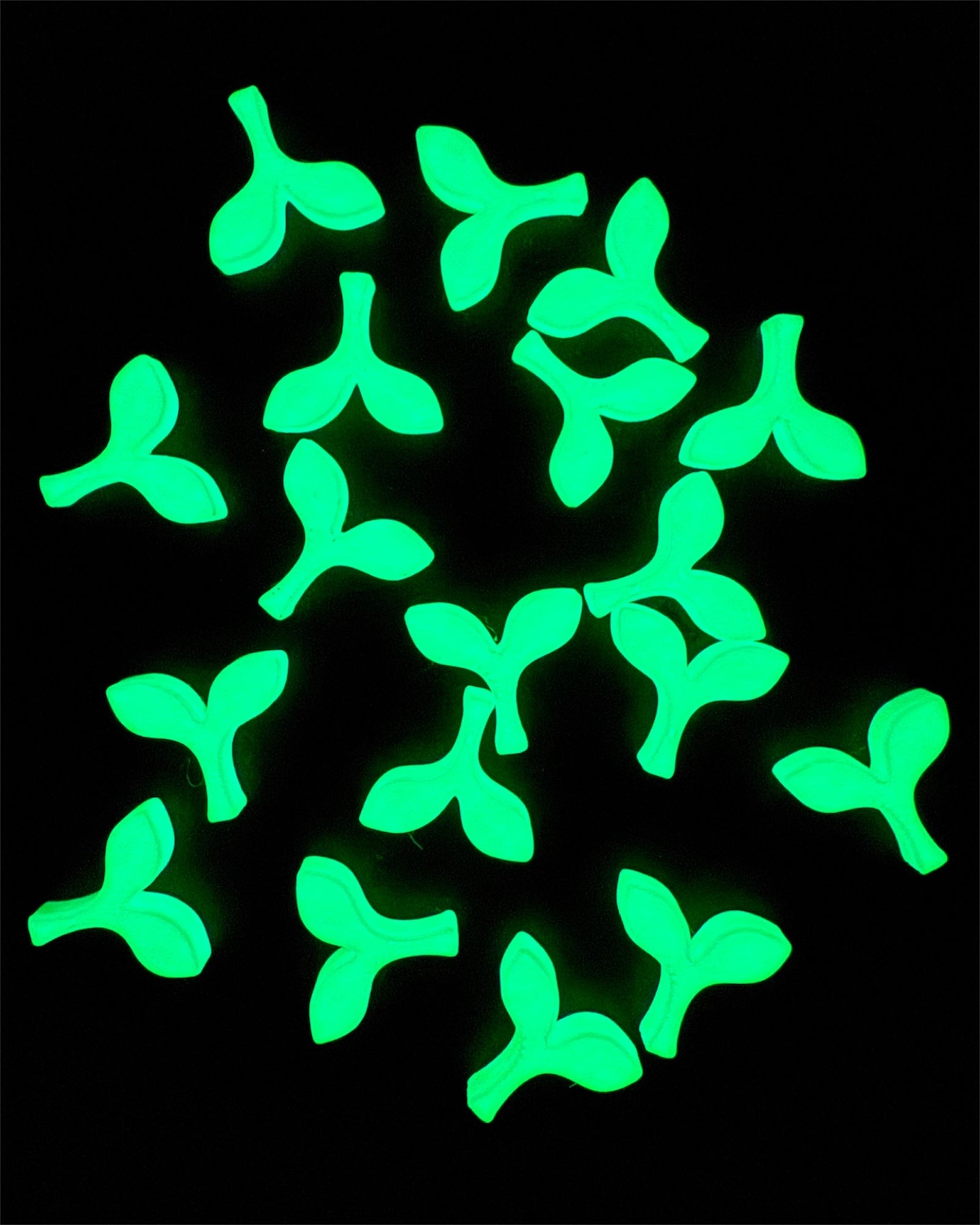 Glow-in-the-dark sprout kandi beads glowing bright green on black background, ideal for rave kandi jewelry.