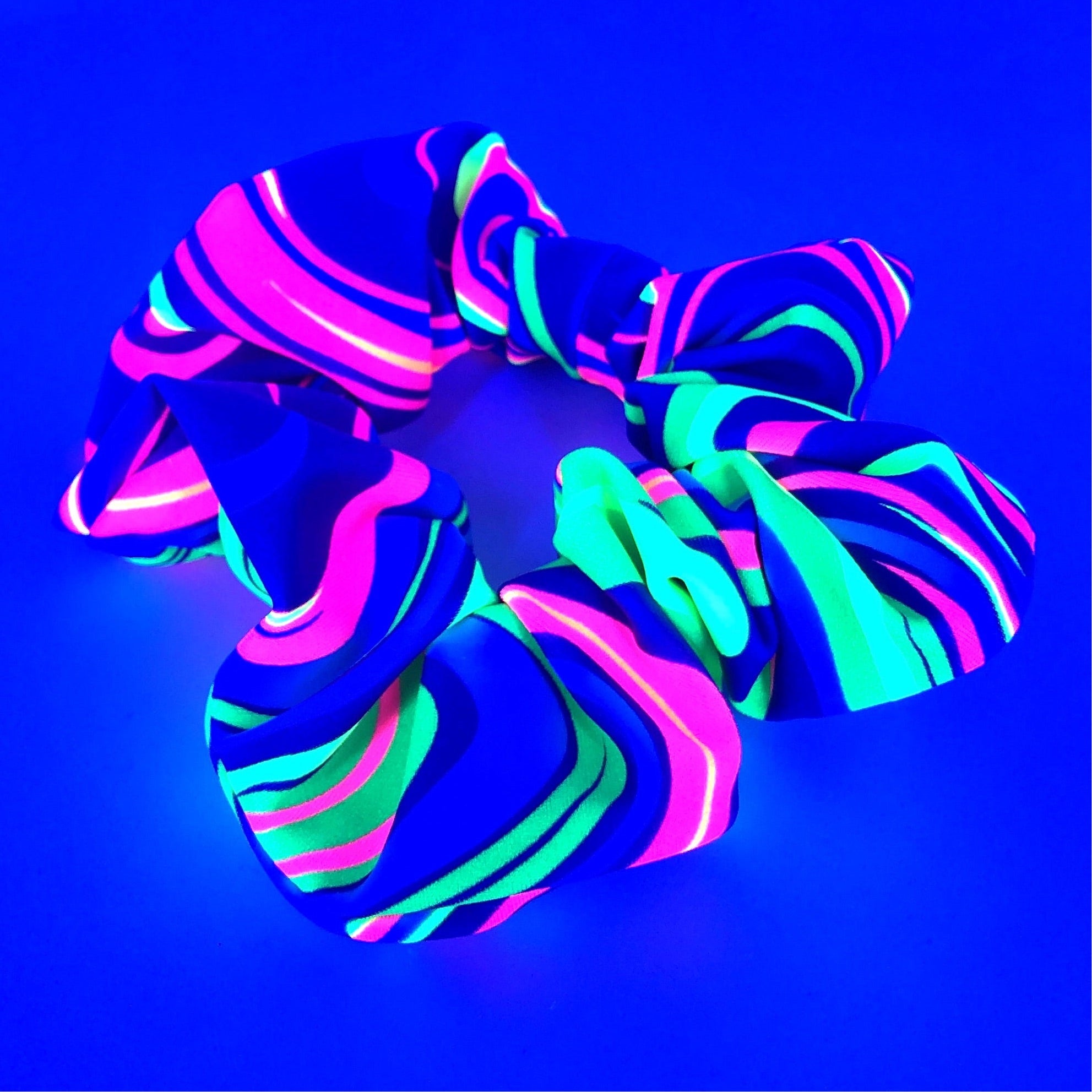 The Kandi Flip Stashie featuring bright neon swirl patterns under black light and a discreet 2-inch Velcro® pocket for small essentials. - one stop rave.