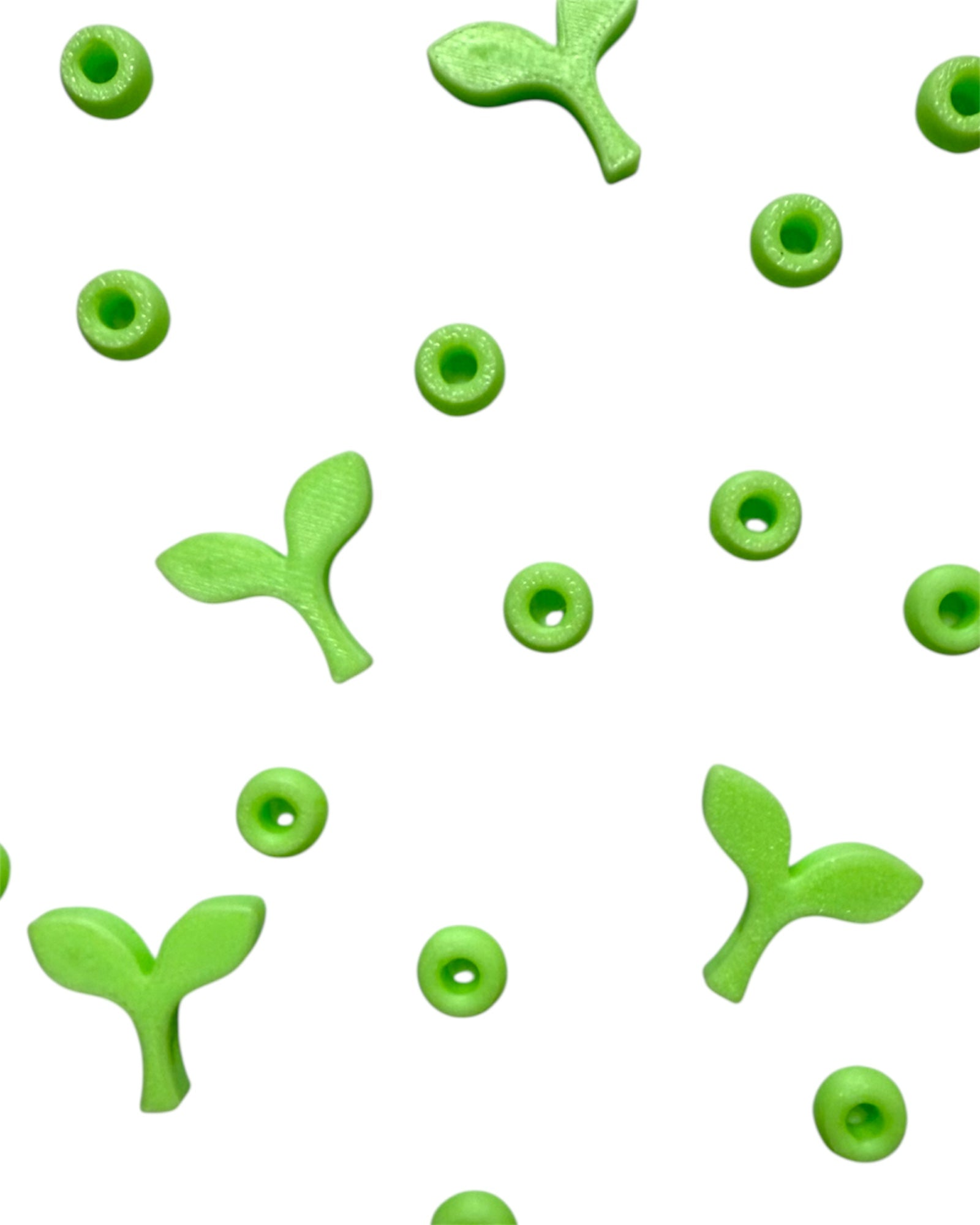 Scattered glow-in-the-dark sprout kandi beads and green spacer beads for making rave kandi bracelets and festival trades.