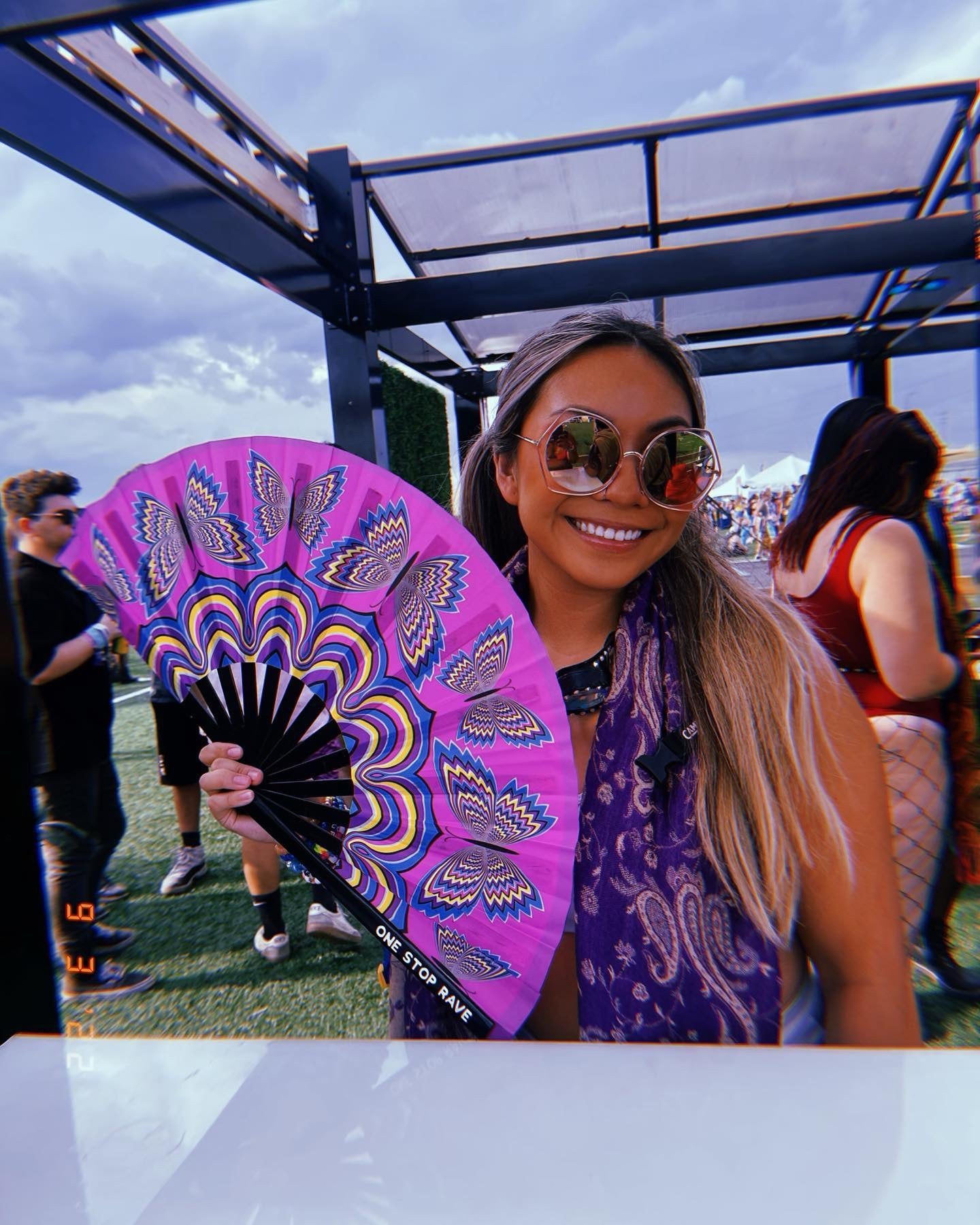 Butterfly Trip hand fan held at festival by smiling woman