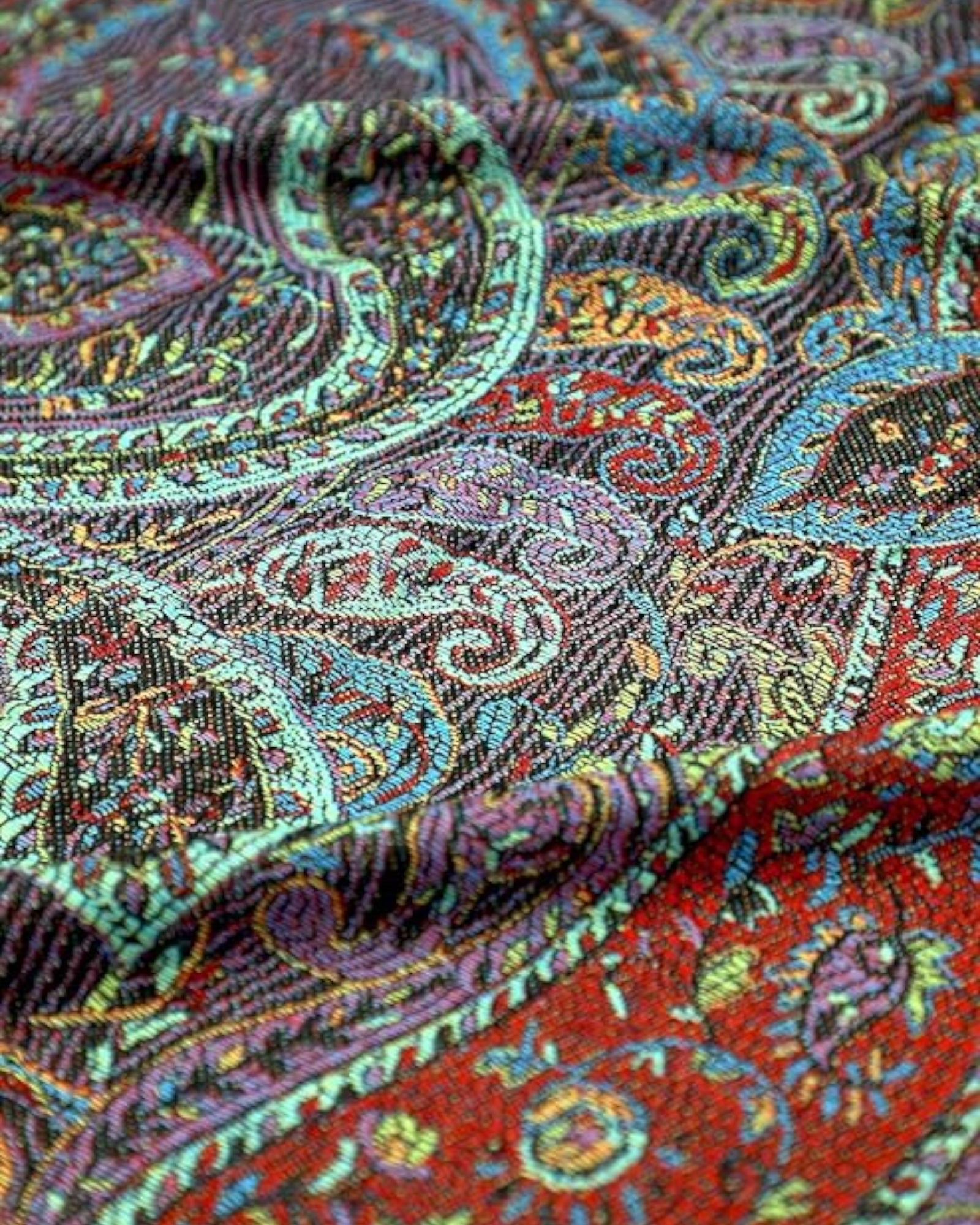 Close up of black pashmina with a paisley pattern spread out, showing off its full length and fringes.