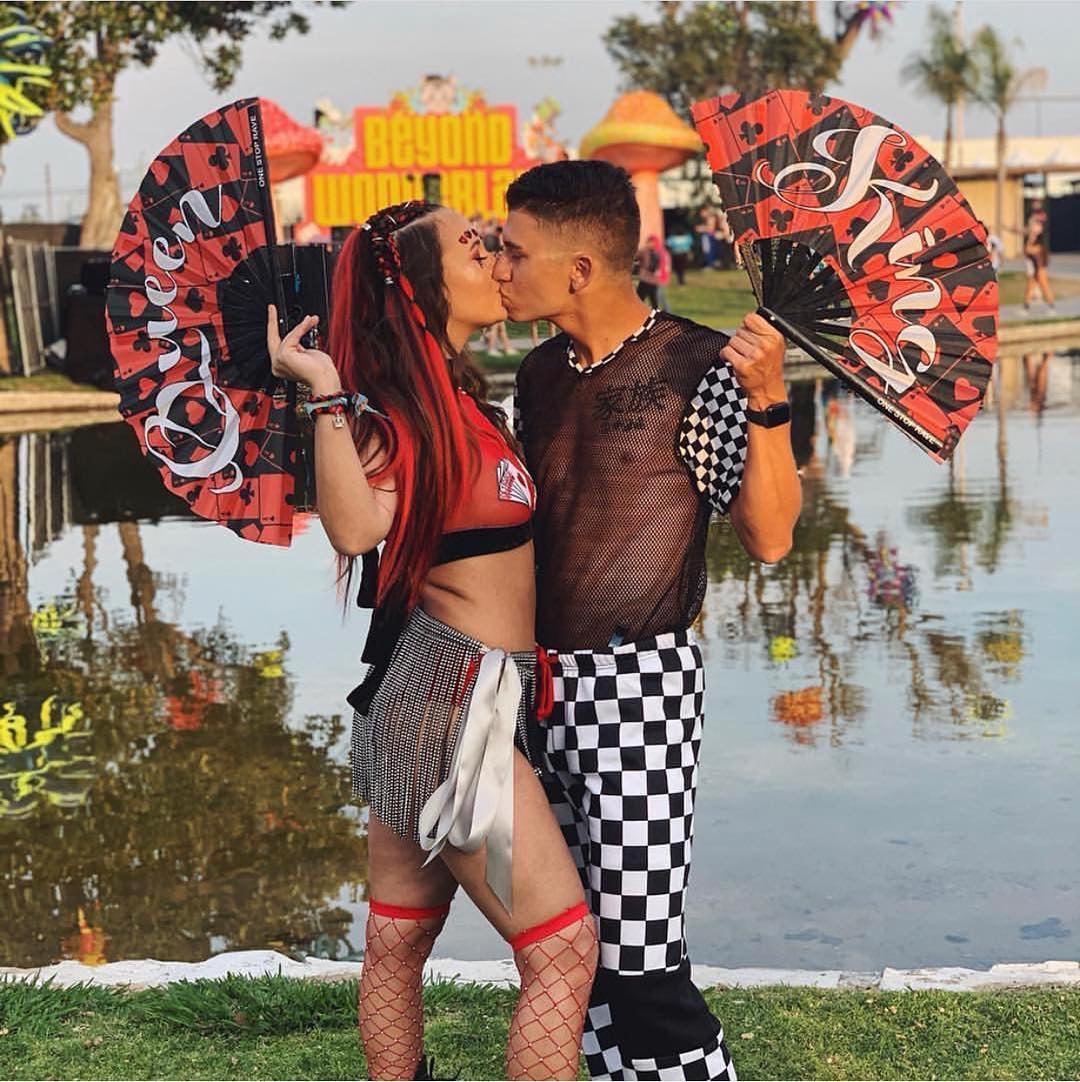 Couple holding King and Queen of Hearts hand fans at Beyond Wonderland festival.