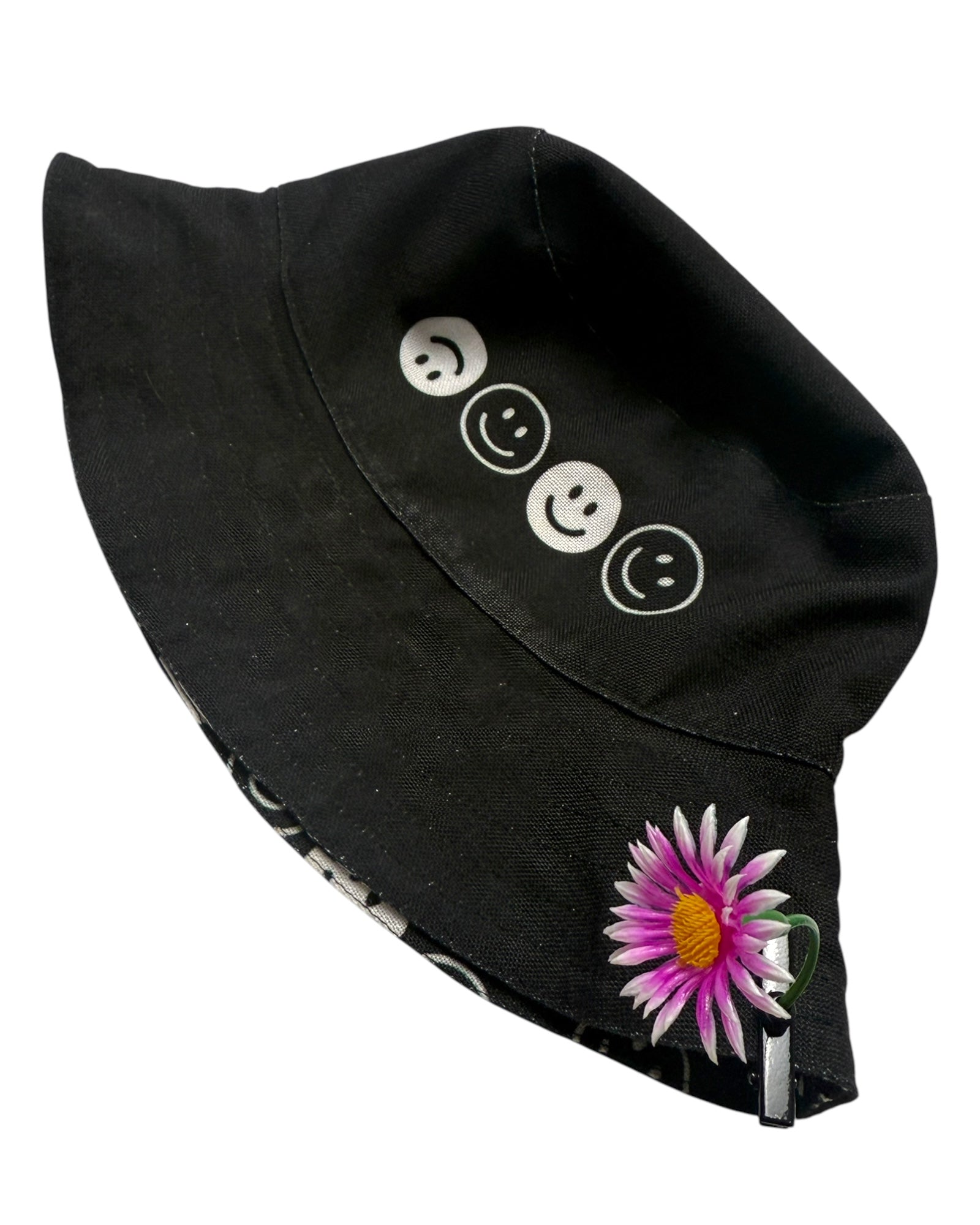 Pink daisy sprout clip attached to black bucket hat on white background.