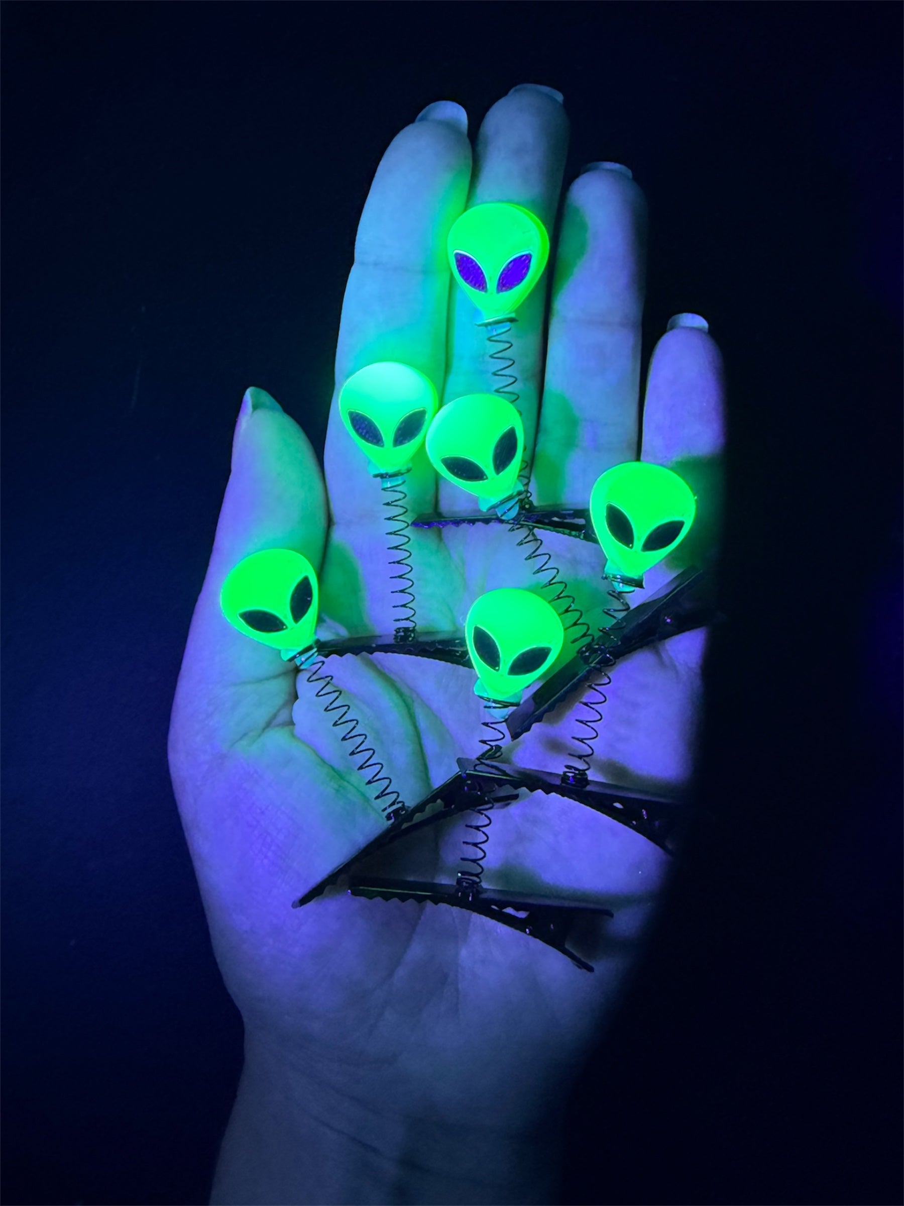 Fluorescent Green Alien Heads in black light being held in a hand.