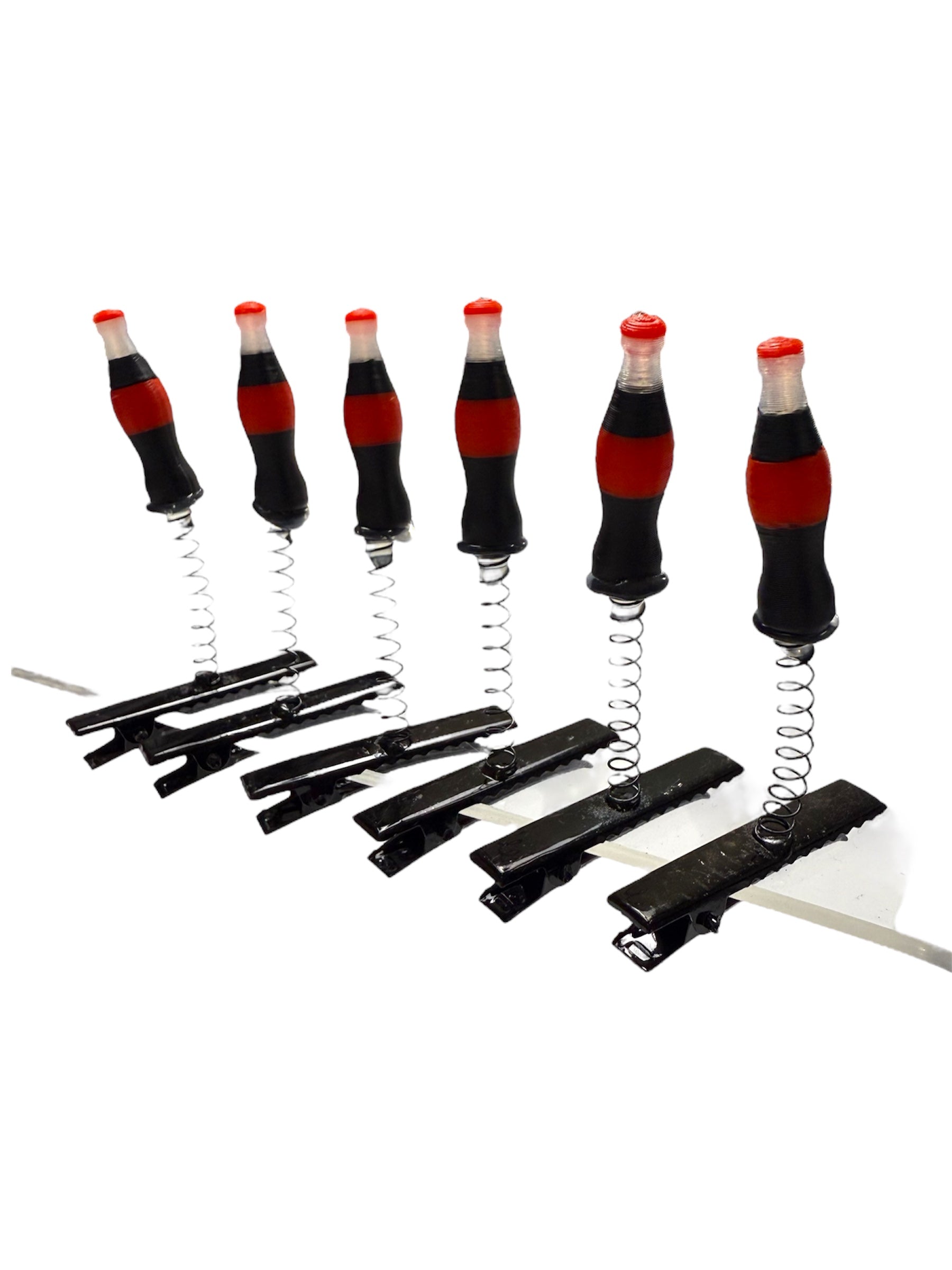 Set of spring-loaded clips with Coca-Cola bottle design handles on a white background