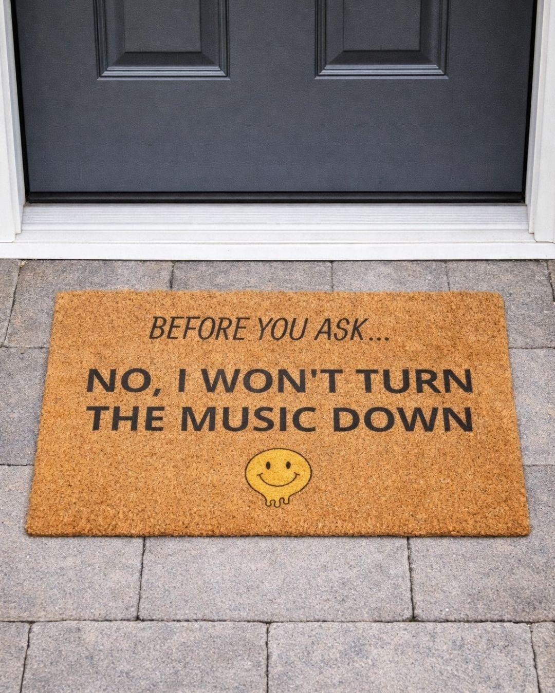 Doormat with humorous text and smiley face on a stone floor in front of a door or camp site.