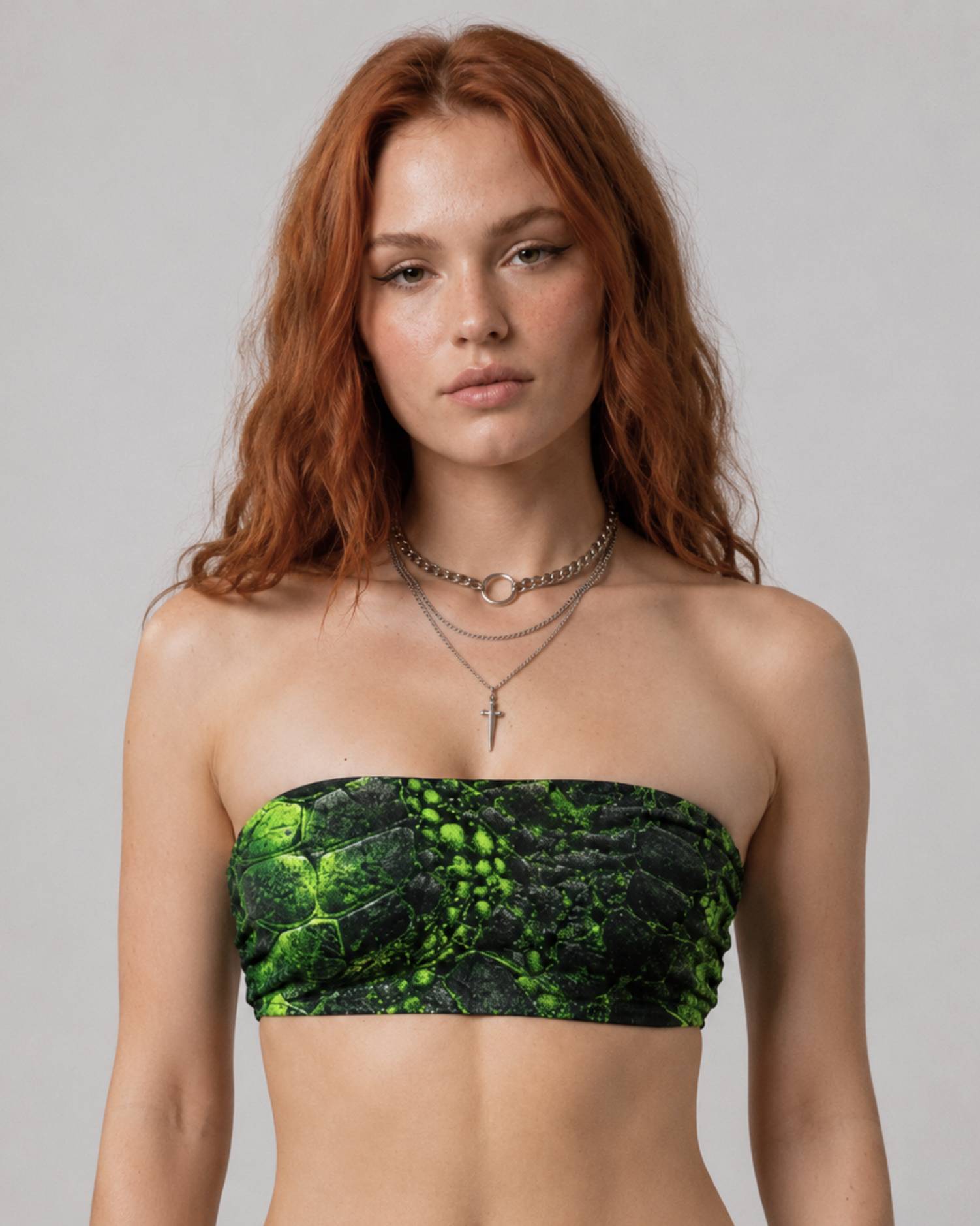 Model wearing a strapless bandeau top with a black and neon green cracked prehistoric-textured print.