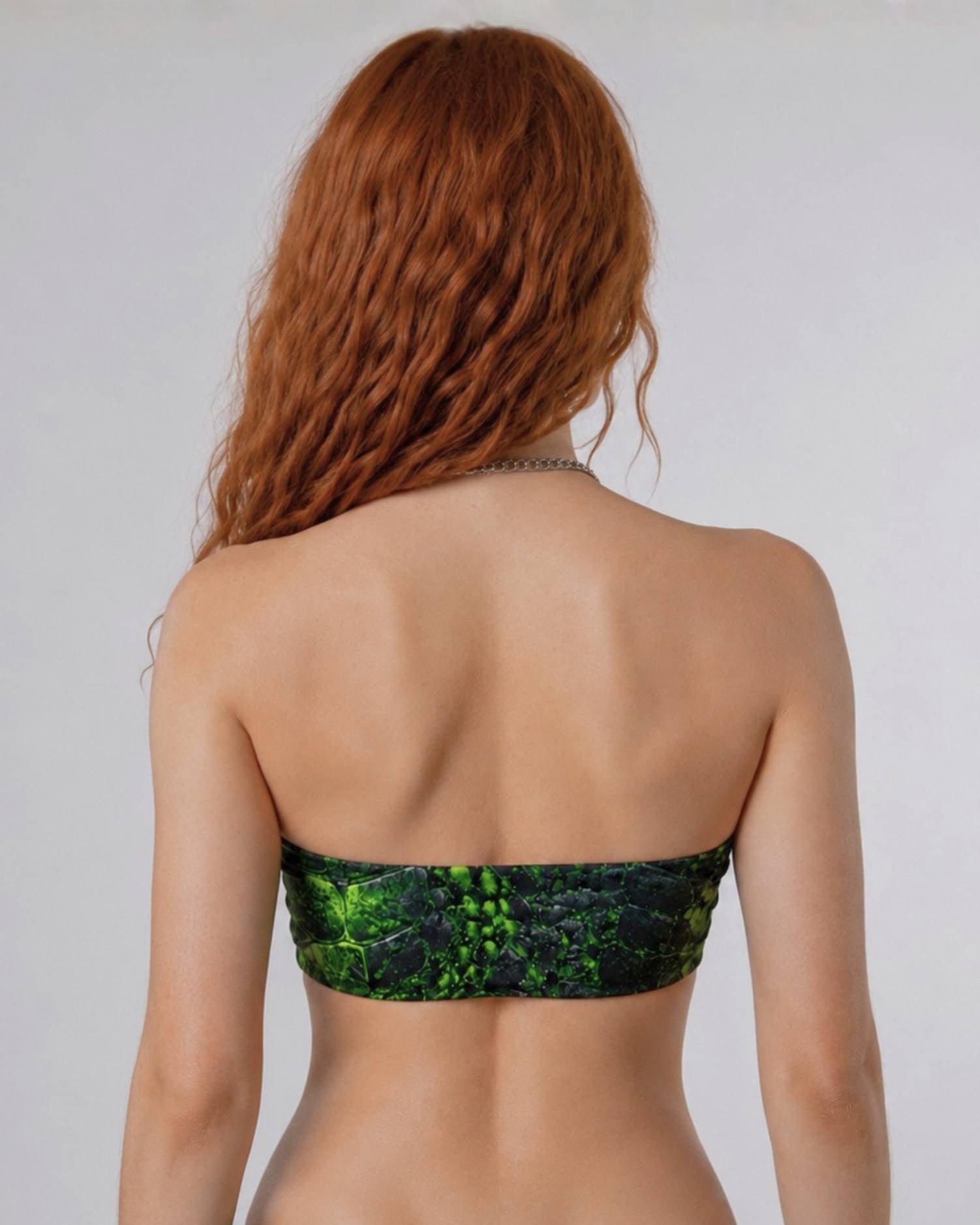 Back view of model wearing the Ravage Bandeau Top in black and neon green cracked prehistoric-inspired print.
