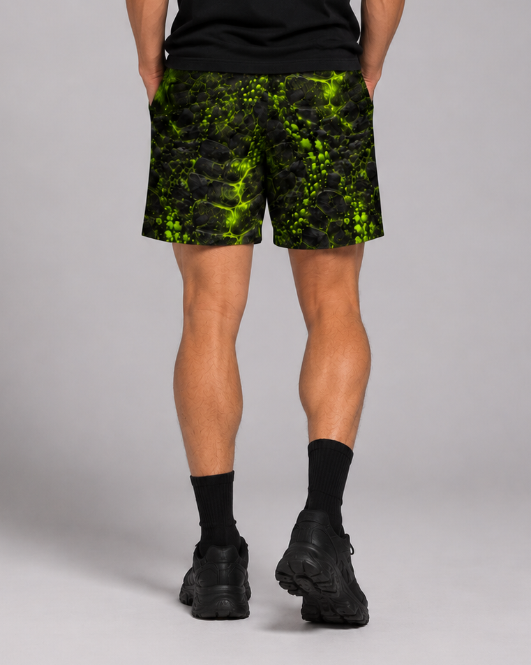 Back view of black athletic shorts with a neon green cracked, prehistoric-textured print, worn with black socks and sneakers.