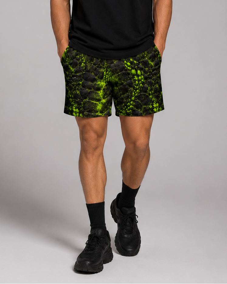 Men's black athletic shorts with neon green cracked, prehistoric-inspired texture print, front view on model.