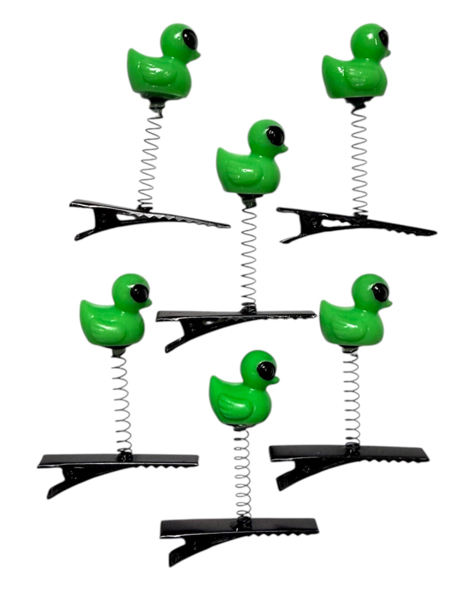 Set of six green alien ducks on black spring with alligator clips on a white background