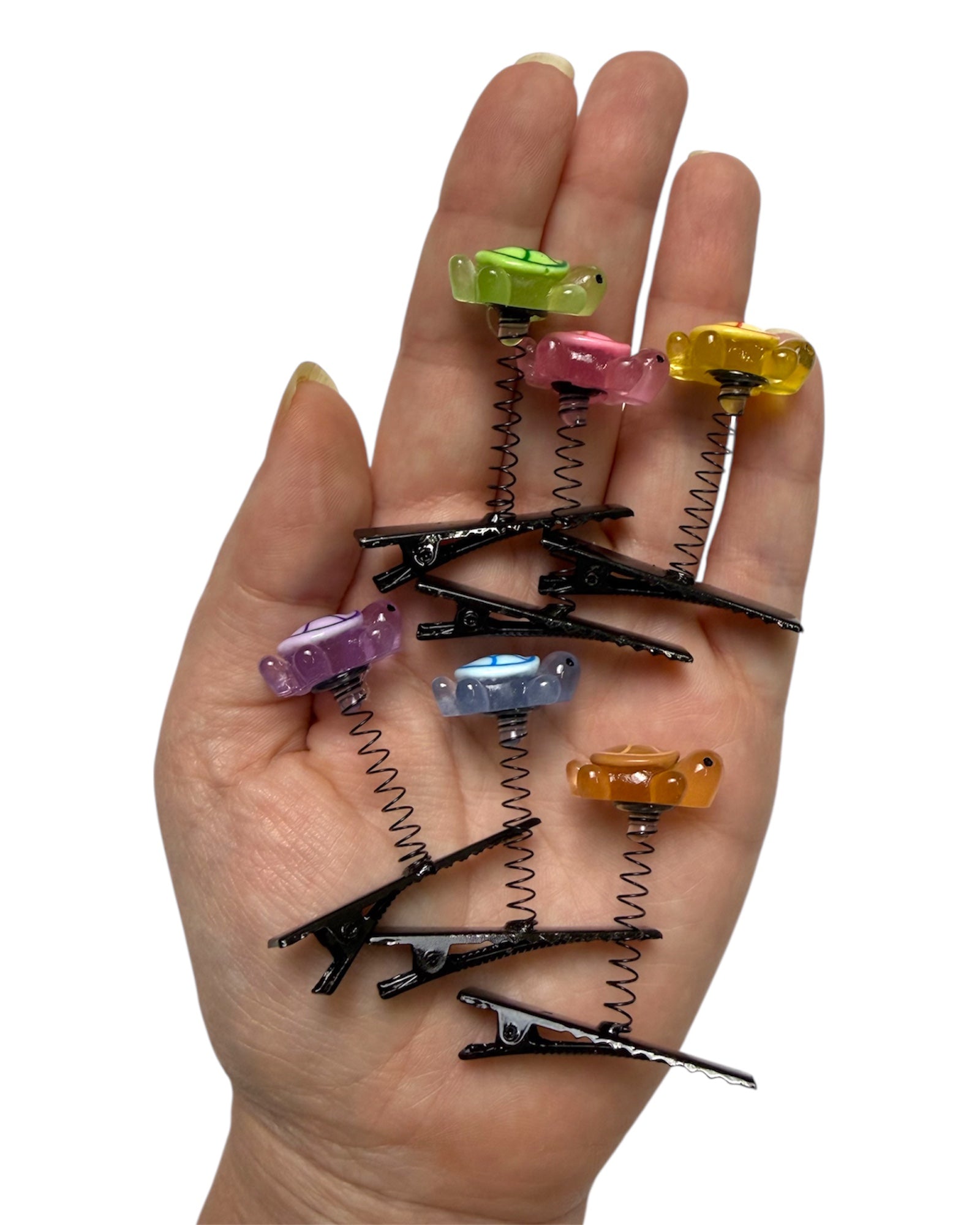 Glow in the dark turtle sprout clips 6-pc set being held in a hand for scale with white backgroud.