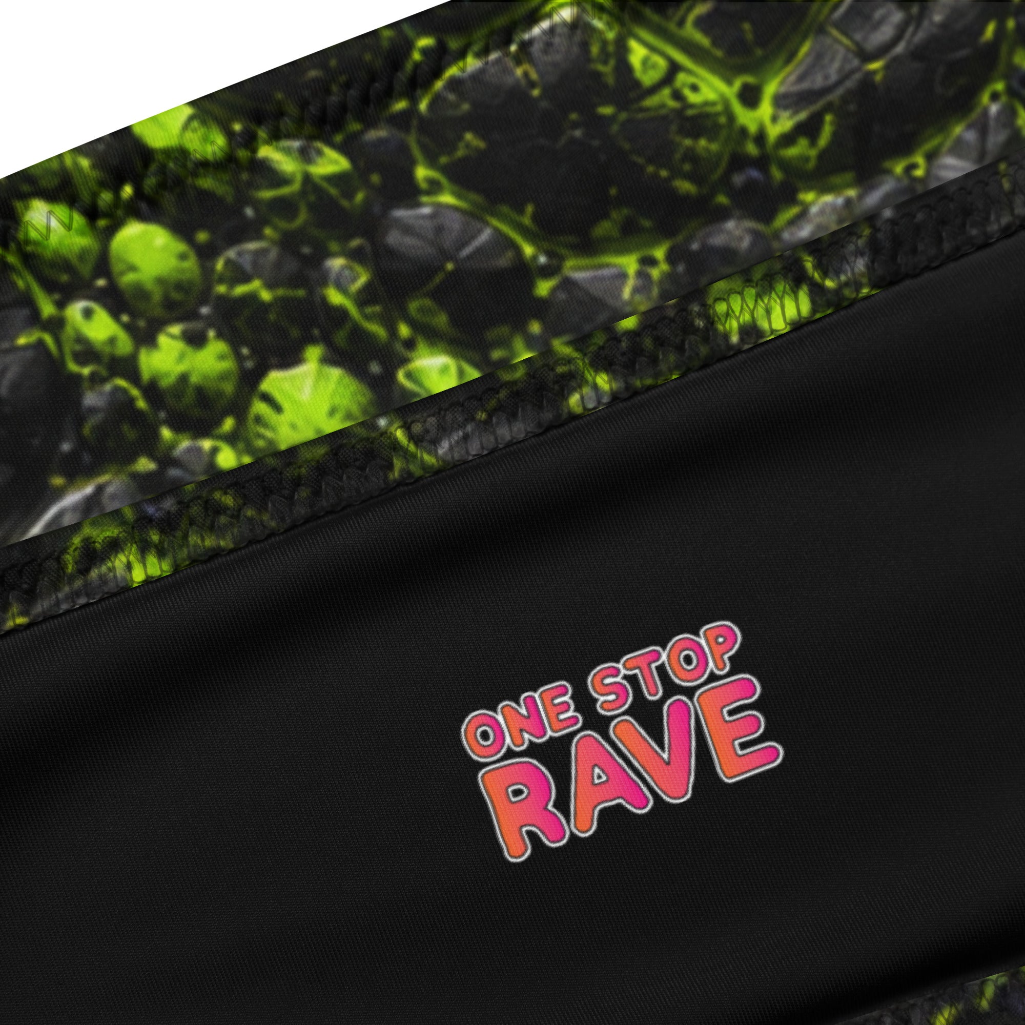Close-up of black bandeau top with neon green cracked texture print and pink "One Stop Rave" logo detail.