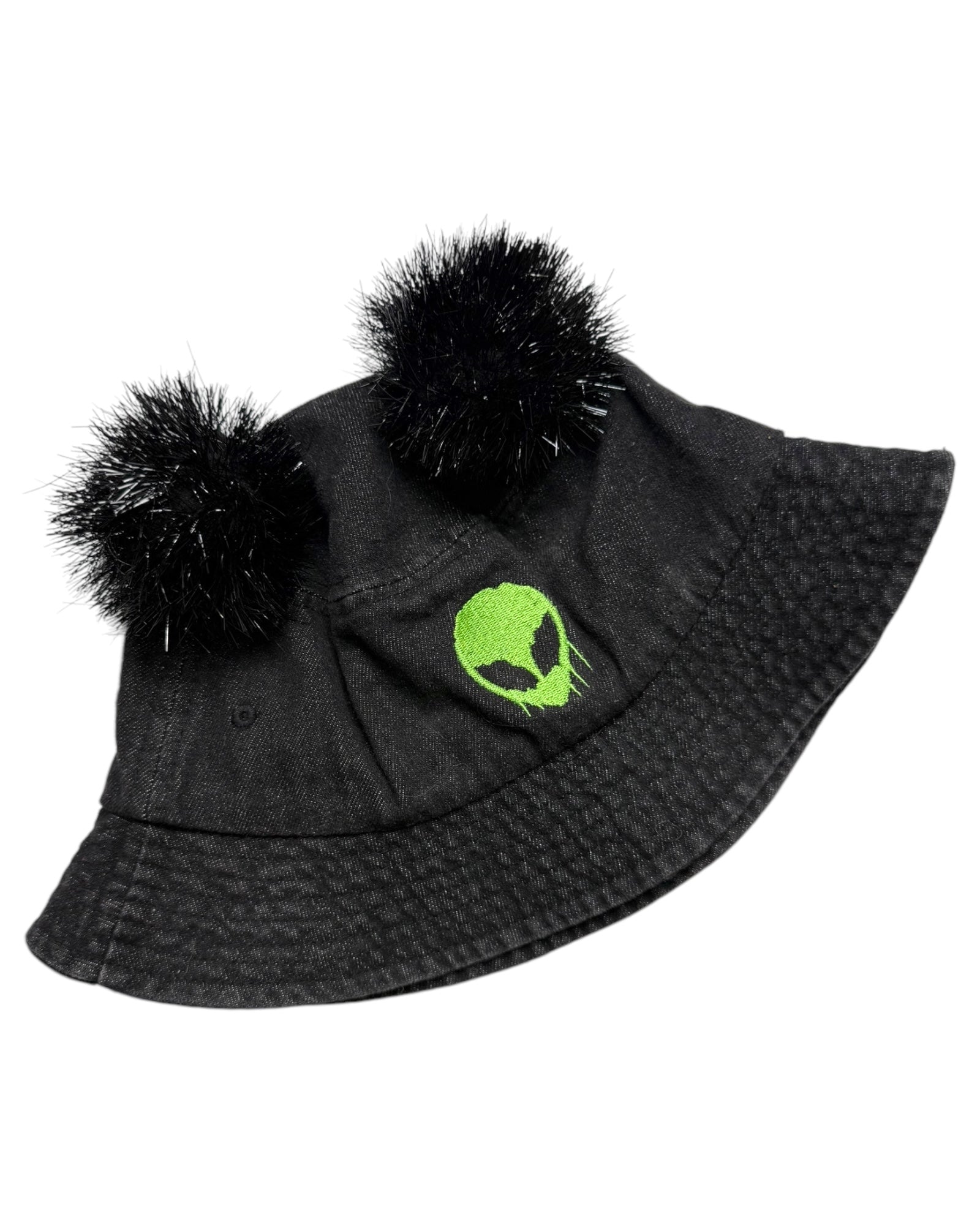 A black bucket hat with black tinsel pom poms and a green skull logo, designed for music festivals and raves.