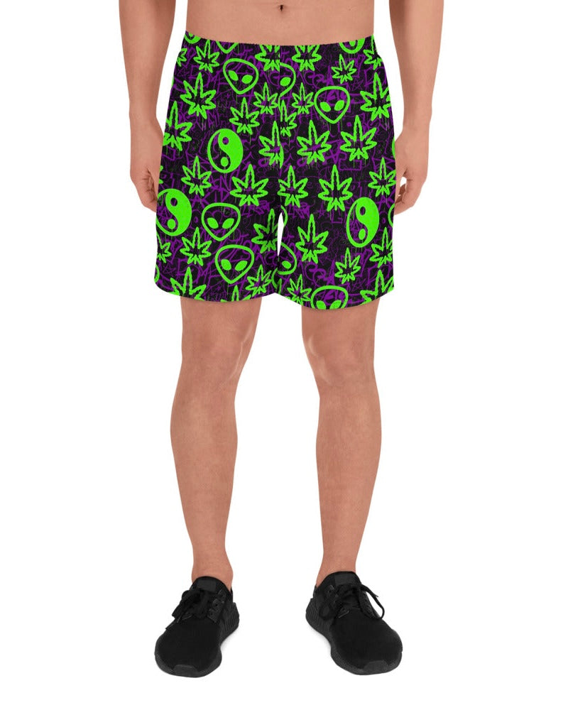 Shorts with green alien and marijuana leaf designs on a model with white background